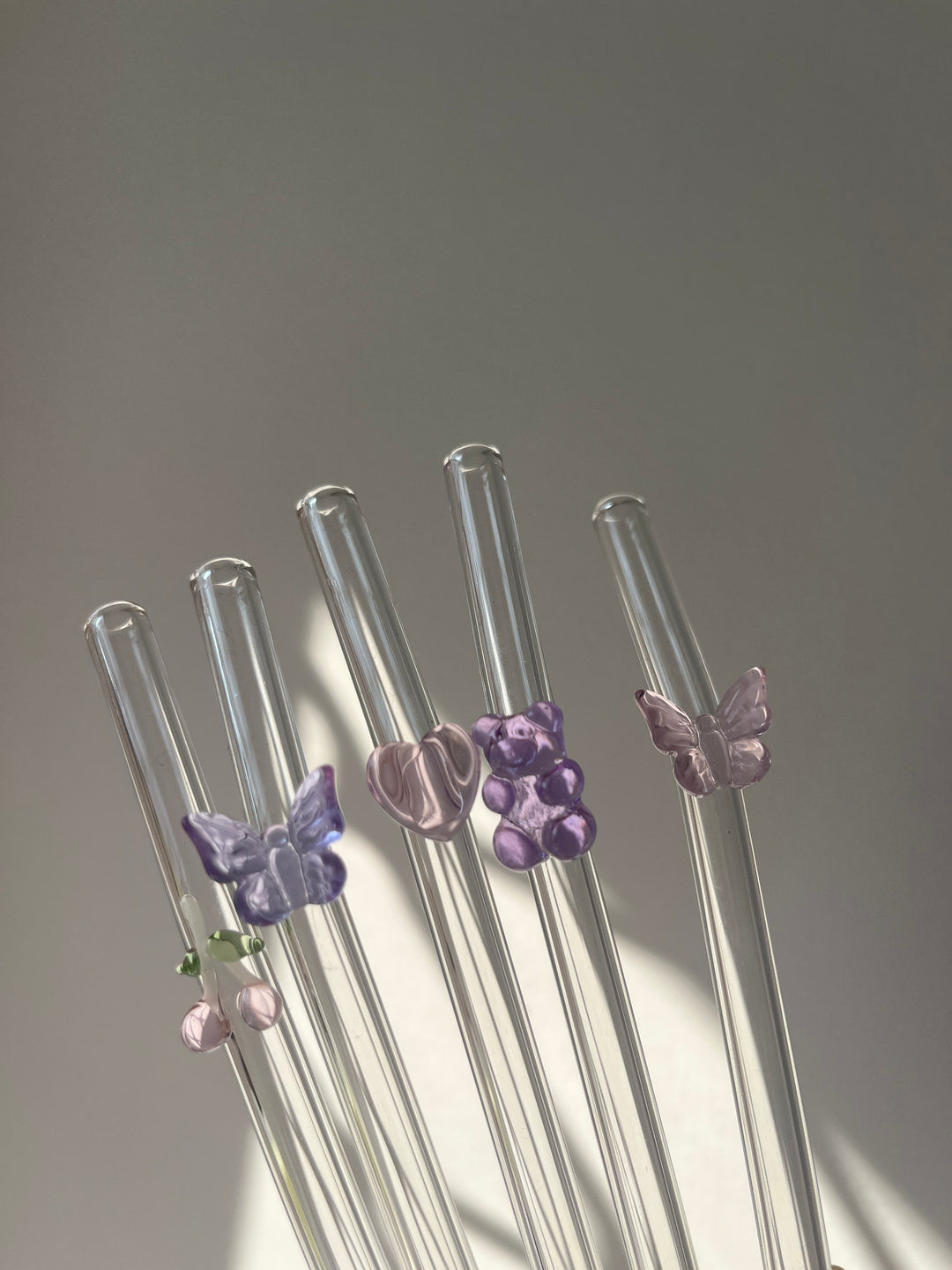 Clear glass straws with colorful butterfly-shaped ends on a gray background