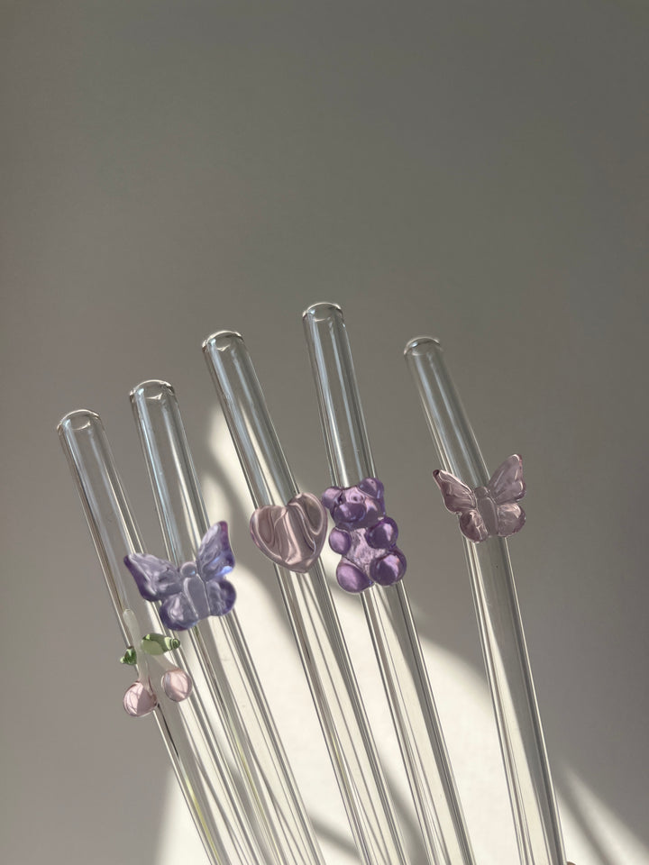 Clear glass straws with colorful butterfly-shaped ends on a gray background