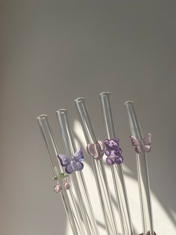 Set of glass straws with decorative butterfly ends on a gray background
