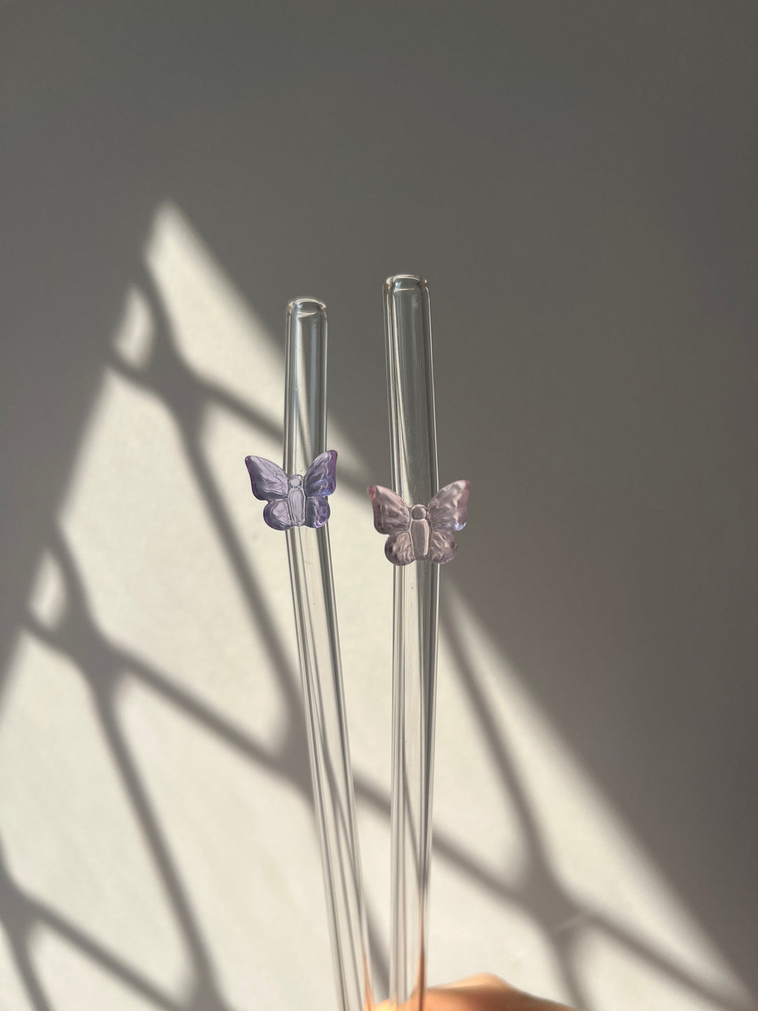 Clear glass straws with butterfly decorations on a gray background
