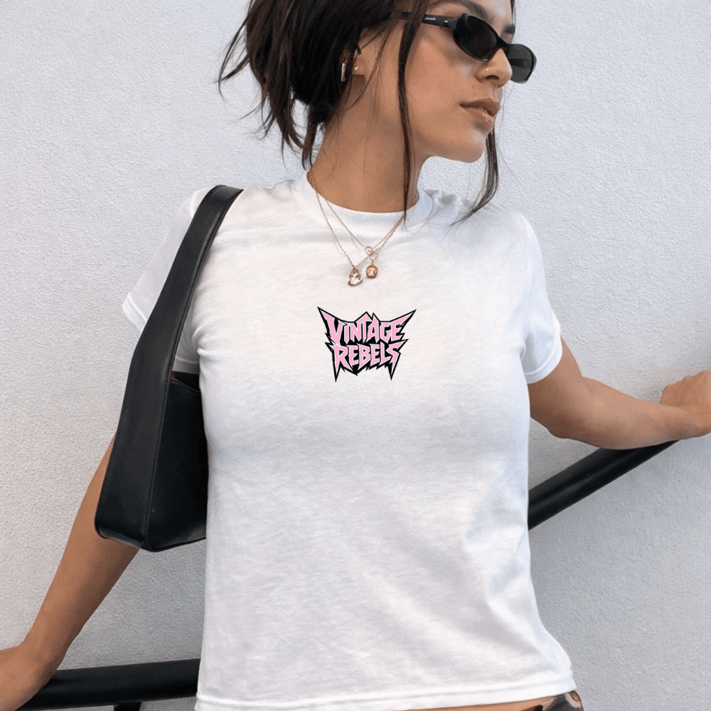 Woman wearing a white t-shirt with 'Vintage Rebels' logo, holding a black bag against a light gray background