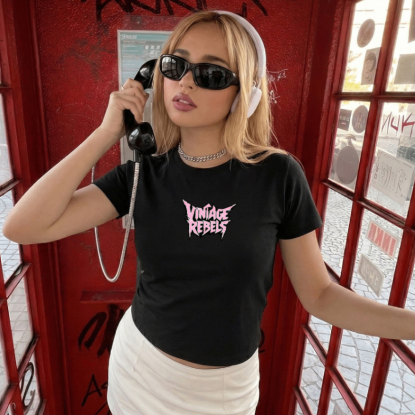 Person wearing a black 'Vintage Rebels' t-shirt in front of a red telephone booth.